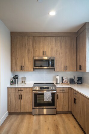 Une cuisine moderne avec des meubles en bois, des appareils en acier inoxydable et un plan de travail blanc.