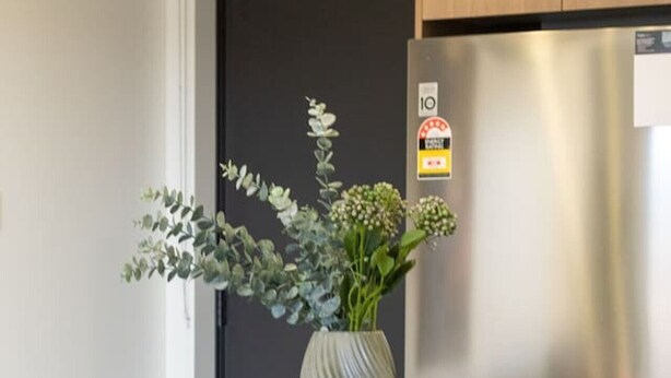 A modern kitchen with a stainless steel refrigerator, a vase with flowers on the table, and contemporary chairs. - City Fringe 2BR 2BA Townhouse | Parking + EV (Christchurch)