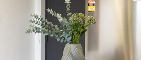 Una cocina moderna con un refrigerador de acero inoxidable, un florero con flores en la mesa y sillas contemporáneas.