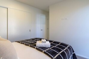 A bedroom with a bed, a wardrobe, and a door. - City Fringe 2BR 2BA Townhouse | Parking + EV (Christchurch)