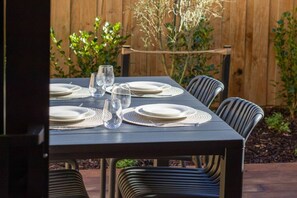 A table set outdoors with plates, glasses, and a placemat. - City Fringe 2BR 2BA Townhouse | Parking + EV (Christchurch)
