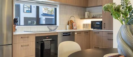 Una cocina moderna con armarios de madera, horno integrado y comedor con mesa y sillas.