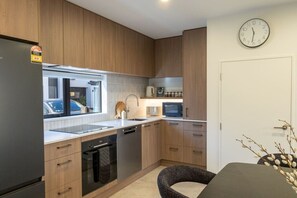 Eine moderne Küche mit Holzschränken, einem eingebauten Geschirrspüler, einer Mikrowelle und einem Fenster mit Blick auf einen Parkplatz.