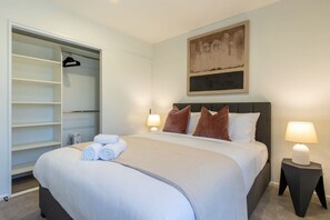 Ein Hotelzimmer mit einem Bett, zwei Nachttischlampen, einem großen Gemälde an der Wand und einem begehbaren Kleiderschrank.
