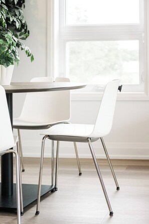 Un comedor moderno con una mesa, sillas, una planta en maceta y una ventana con vistas.