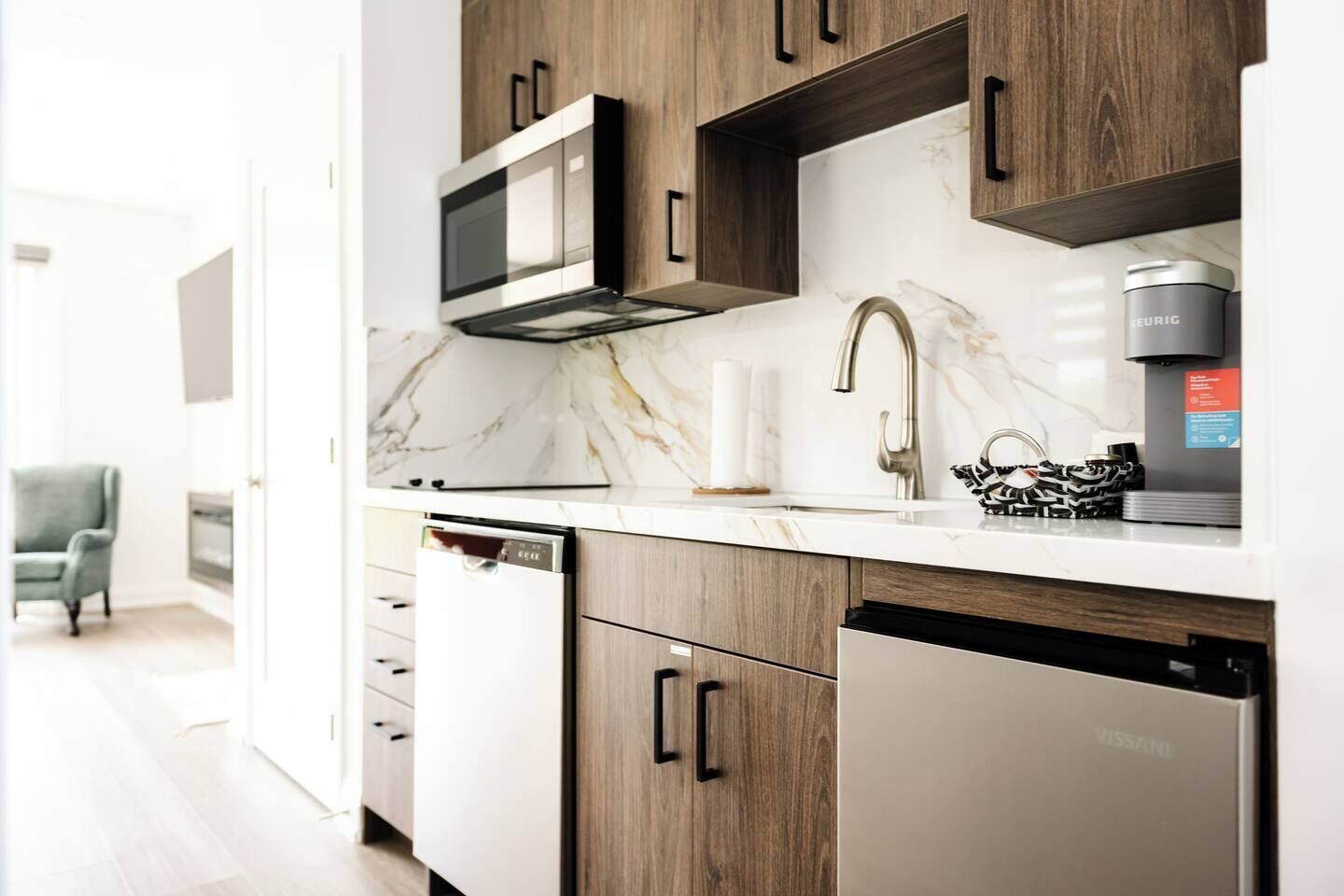 A modern kitchen with a built-in microwave, a coffee maker, and a dishwasher.