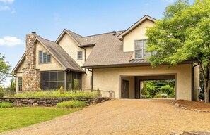 A two-story house with a stone chimney, large windows, and a covered driveway. - McLemore Resort - 856 Canyon Ridge Road - French Country Home - Walking distance to Range and Clubhouse (Rising Fawn)
