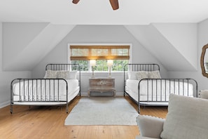 Un dormitorio con dos camas, una ventana con persianas, una mesita de noche y una silla.