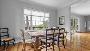 Un comedor con mesa y sillas de madera, ventanas amplias y vistas al exterior.