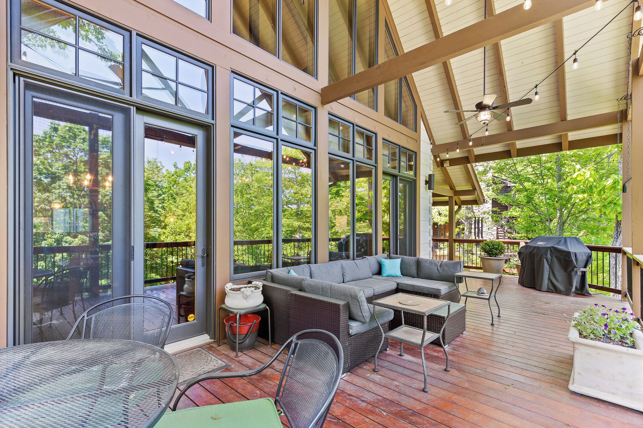 A covered outdoor deck with a sofa, chairs, and a grill area.