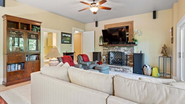 A living room with a sectional sofa, a television, a fireplace, and a ceiling fan. - McLemore Resort - 33 Eagle Creek Trail - Forest Cabin (Rising Fawn)
