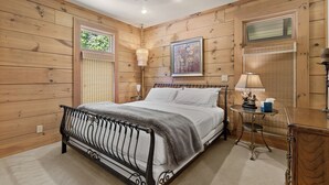 A bedroom with a bed, bedside lamps, a window, and a painting on the wall. - McLemore Resort - 33 Eagle Creek Trail - Forest Cabin (Rising Fawn)