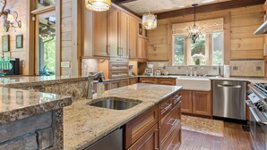 A spacious kitchen with granite countertops, stainless steel appliances, and wooden cabinetry. - McLemore Resort - 33 Eagle Creek Trail - Forest Cabin (Rising Fawn)
