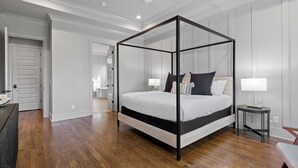 A bedroom with a four-poster bed, a bedside table with a lamp, and a view of a bathroom through an open door. - McLemore Resort - 207 Rushing Water Trail - Golf Course View (Rising Fawn)