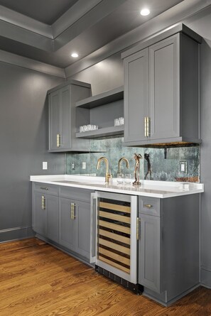 Eine moderne Küche mit grauen Schränken, einer weißen Arbeitsplatte und einer Spritzschutzwand im Used-Look.
