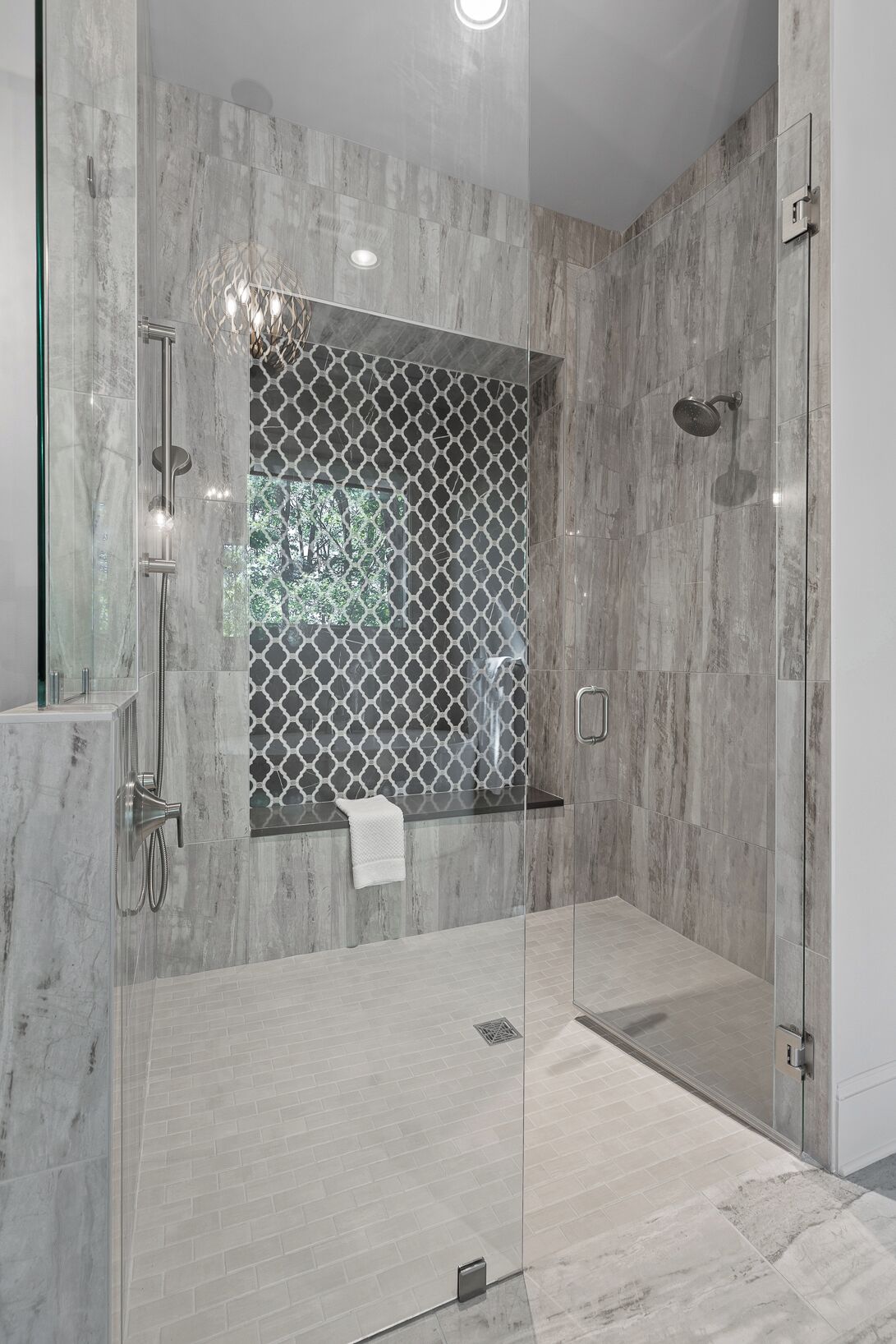 A modern shower with a glass door, a handheld showerhead, and a wall-mounted faucet.