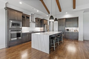 Una cucina moderna con mobili in legno scuro, elettrodomestici in acciaio inossidabile e un'isola in marmo con sgabelli da bar.