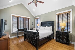 Ein Schlafzimmer mit einem großen Bett, zwei Nachttischen, einem Deckenventilator und einem Fernseher.