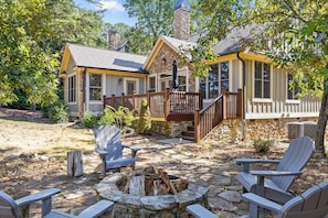 Eine Holzhütte mit Steinofen, einer Holzterrasse und einer Sitzgruppe im Freien mit Adirondack-Stühlen.