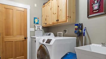 A laundry room with a washing machine, dryer, wooden cabinets, a sink, and a framed picture on the wall.