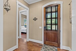 Un couloir avec une porte en bois, un mur blanc et un plancher en bois.