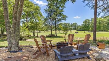 A seating area with Adirondack chairs, a fire pit, and a view of a golf course.