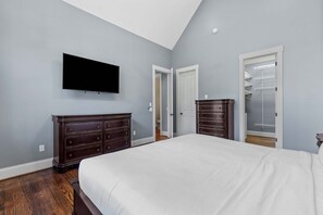 Une chambre à coucher avec un grand lit, une commode, un téléviseur et un dressing.