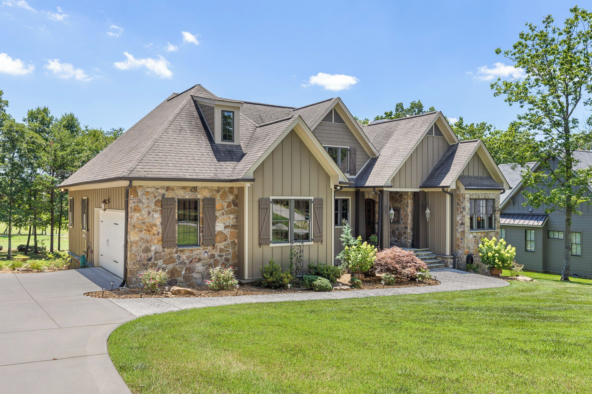 A two-story house with a stone facade, a covered front porch, and a well-maintained lawn.