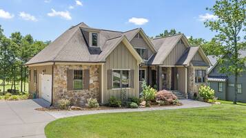 A two-story house with a stone facade, a covered front porch, and a well-maintained lawn.
