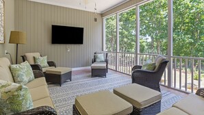 A sunroom with a ceiling fan, a flat-screen TV, wicker furniture, and a view of trees through large windows. - McLemore Resort - 454 Rushing Water Trail - Golf Course View (Rising Fawn)