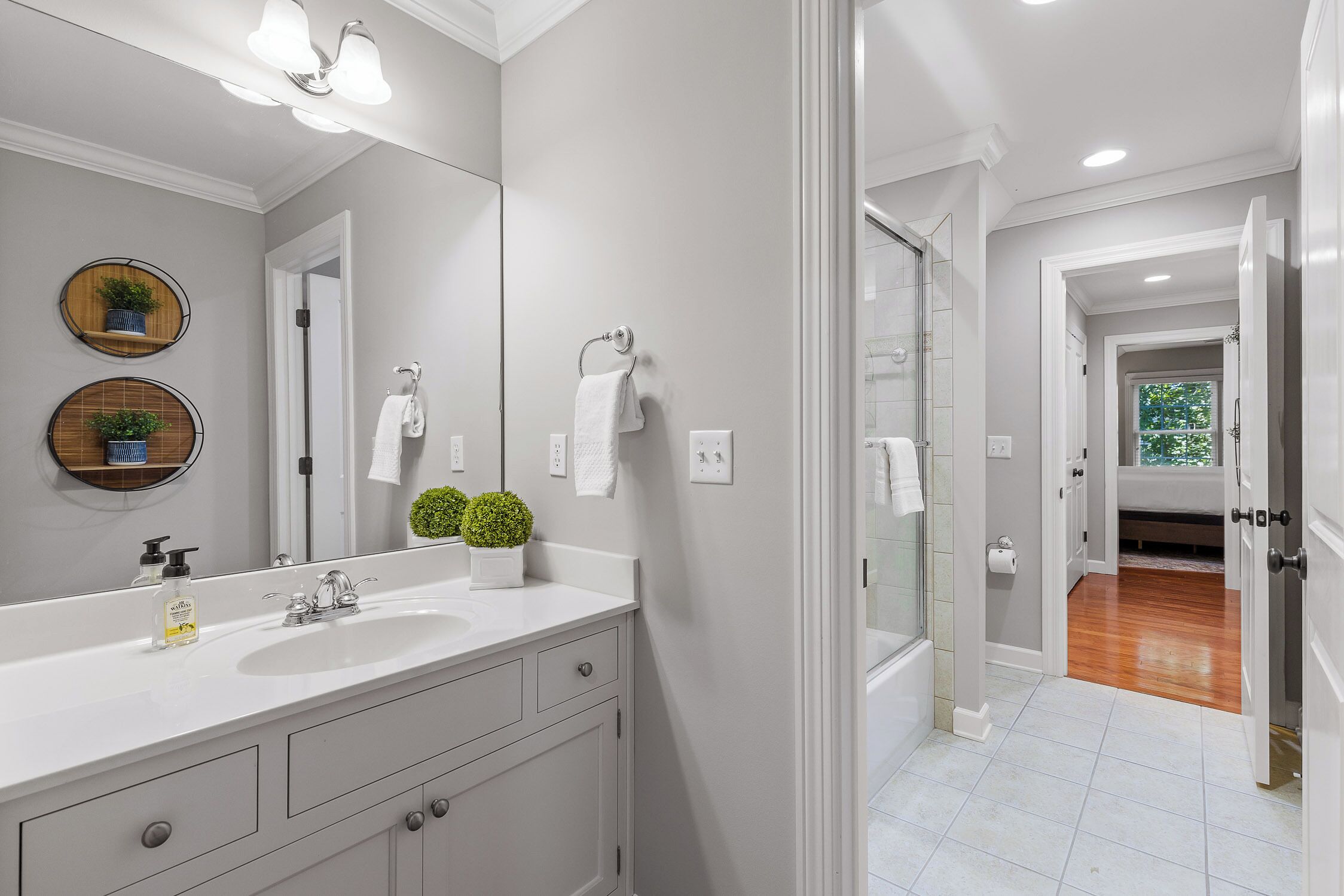 A bathroom with a large mirror, two sinks, a shower, and a toilet.