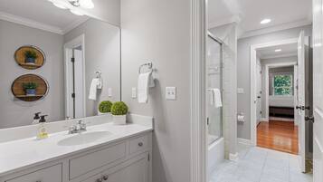 A bathroom with a large mirror, two sinks, a shower, and a toilet.