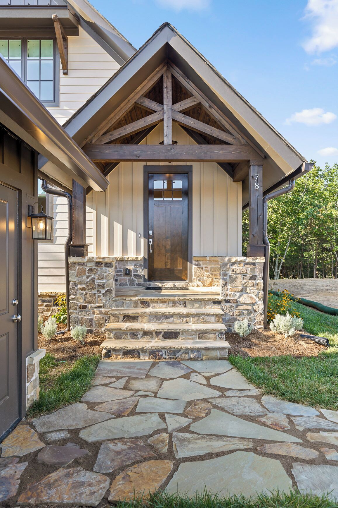 A house with a stone entryway, a wooden door, and a stone staircase leading to the front door.