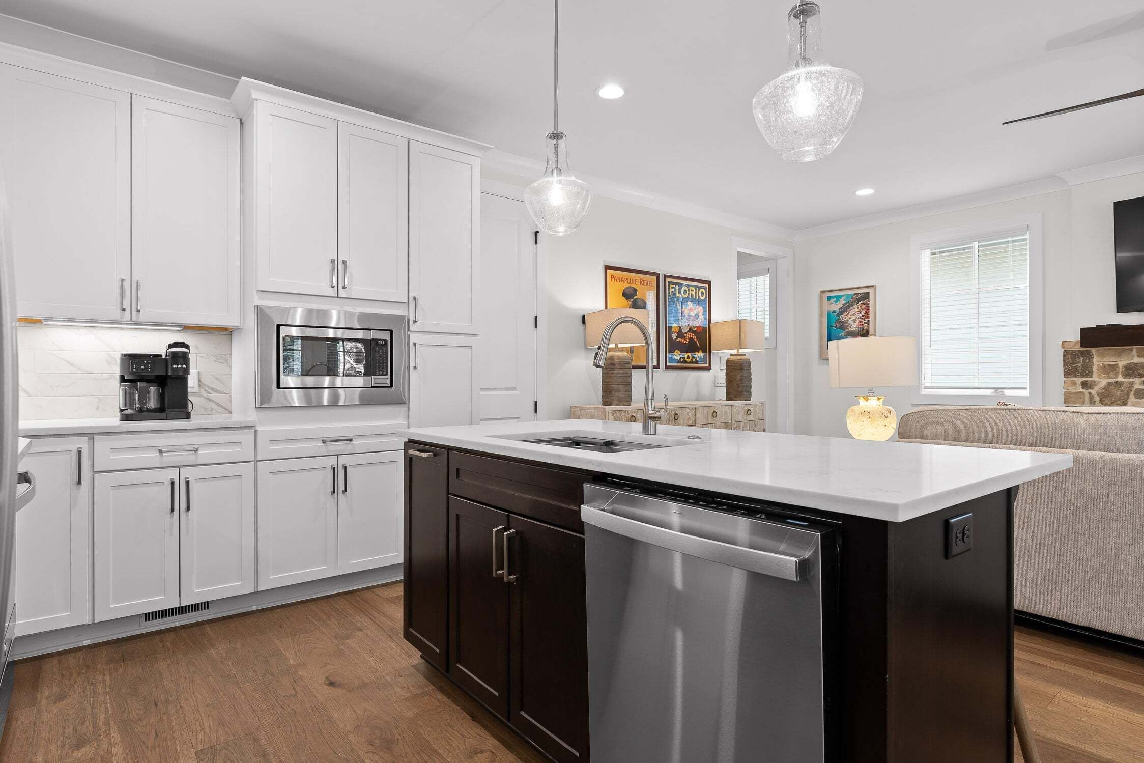 A modern kitchen with white cabinetry, stainless steel appliances, and a central island with a dishwasher.