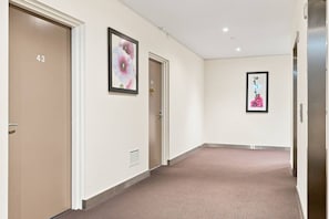 A hallway with beige carpet, doors numbered 43 and 46, and framed floral artwork on the walls.
