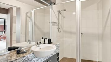 A modern bathroom with a glass-enclosed shower, two sinks, and a marble countertop.