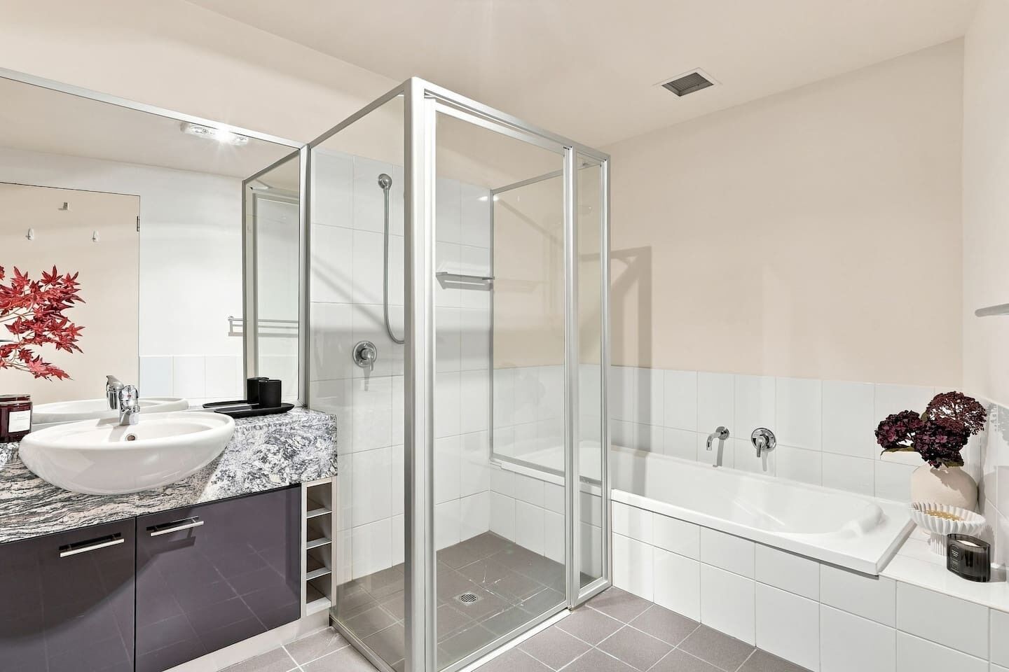 A modern bathroom with a glass-enclosed shower, a white sink with a marble countertop, and a bathtub.