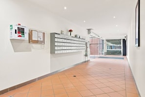 A clean, modern hallway with a tiled floor, a wall-mounted AED box, and a row of drawers.