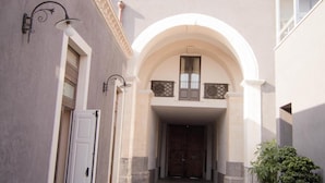 Un patio con un arco central, suelo de piedra y plantas en macetas.
