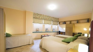 Habitación de hotel con dos camas, un escritorio, una silla, una mesita y un ventanal con cortinas.