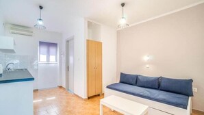 Una sala de estar moderna con un sofá, una mesa de centro y una zona de cocina con un lavamanos y armarios.