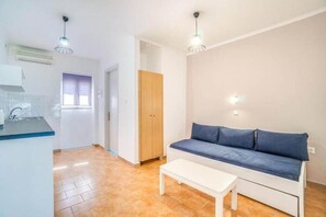 Una sala de estar moderna con un sofá, una mesa de centro y una zona de cocina con un lavamanos y armarios.