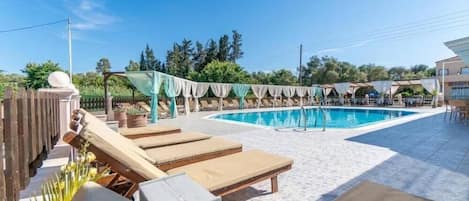 Uma área de piscina com espreguiçadeiras e um espaço de estar coberto.