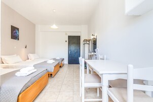 Habitación de hotel con dos camas, una mesa de comedor y zona de ducha.