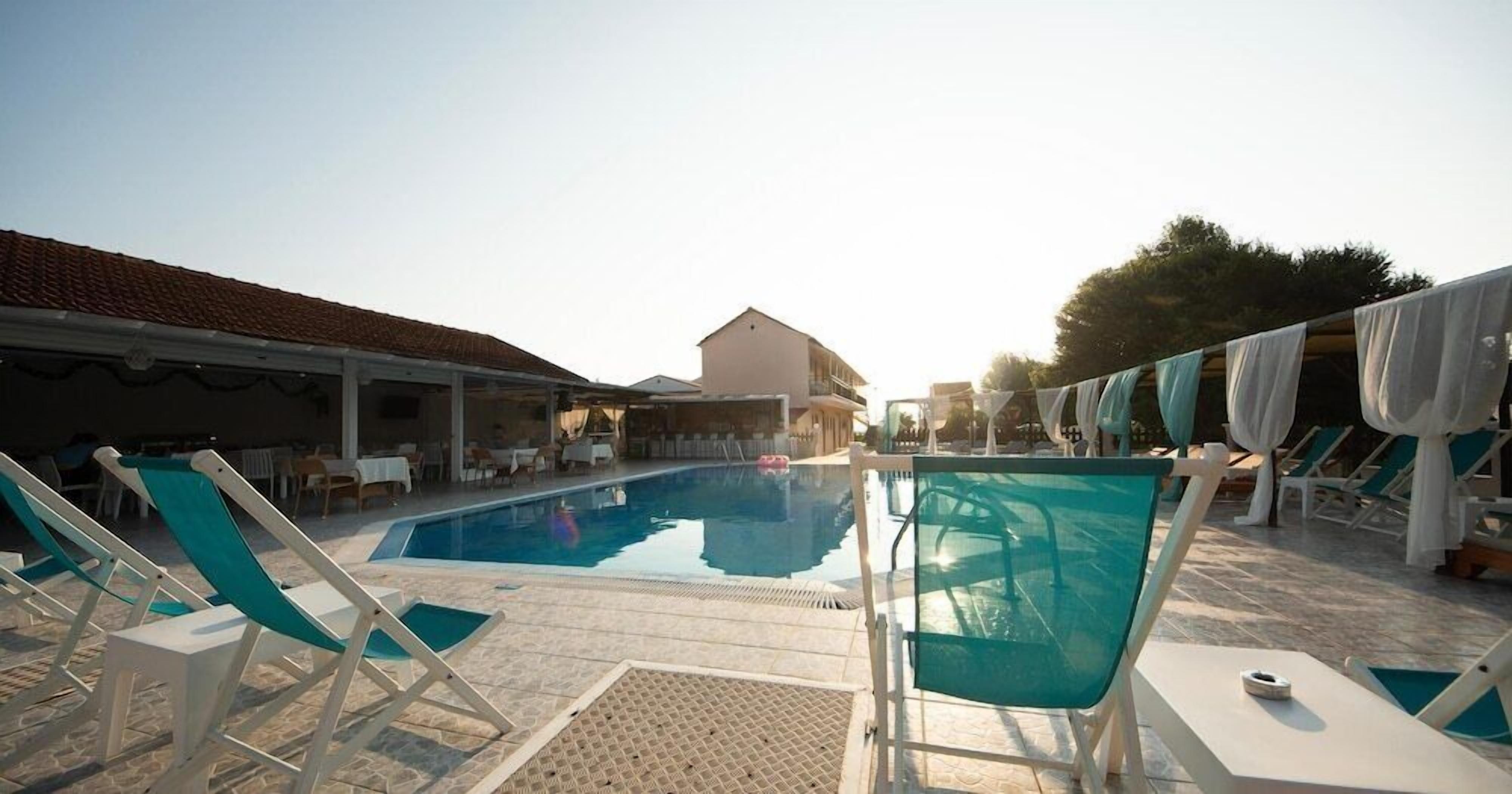 Ein Poolbereich mit Liegestühlen und einem Gebäude im Hintergrund.