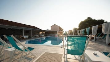 Ein Poolbereich mit Liegestühlen und einem Gebäude im Hintergrund.