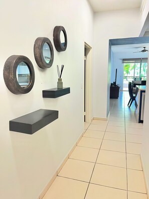 A hallway with a modern design, featuring wall-mounted shelves and mirrors. - Playa Royale Beachfront Family Condo °BBQ, Terrace & Garden Views° (Nuevo Nayarit)