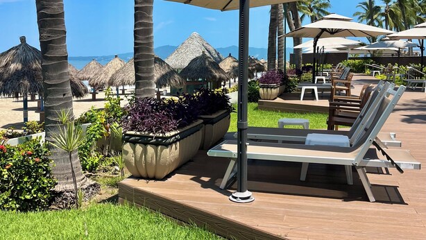 A resort pool area with lounge chairs, umbrellas, and palm trees. - Playa Royale Beachfront Family Condo °BBQ, Terrace & Garden Views° (Nuevo Nayarit)