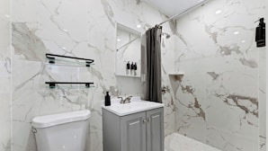 A modern bathroom with a toilet, sink, and shower area.