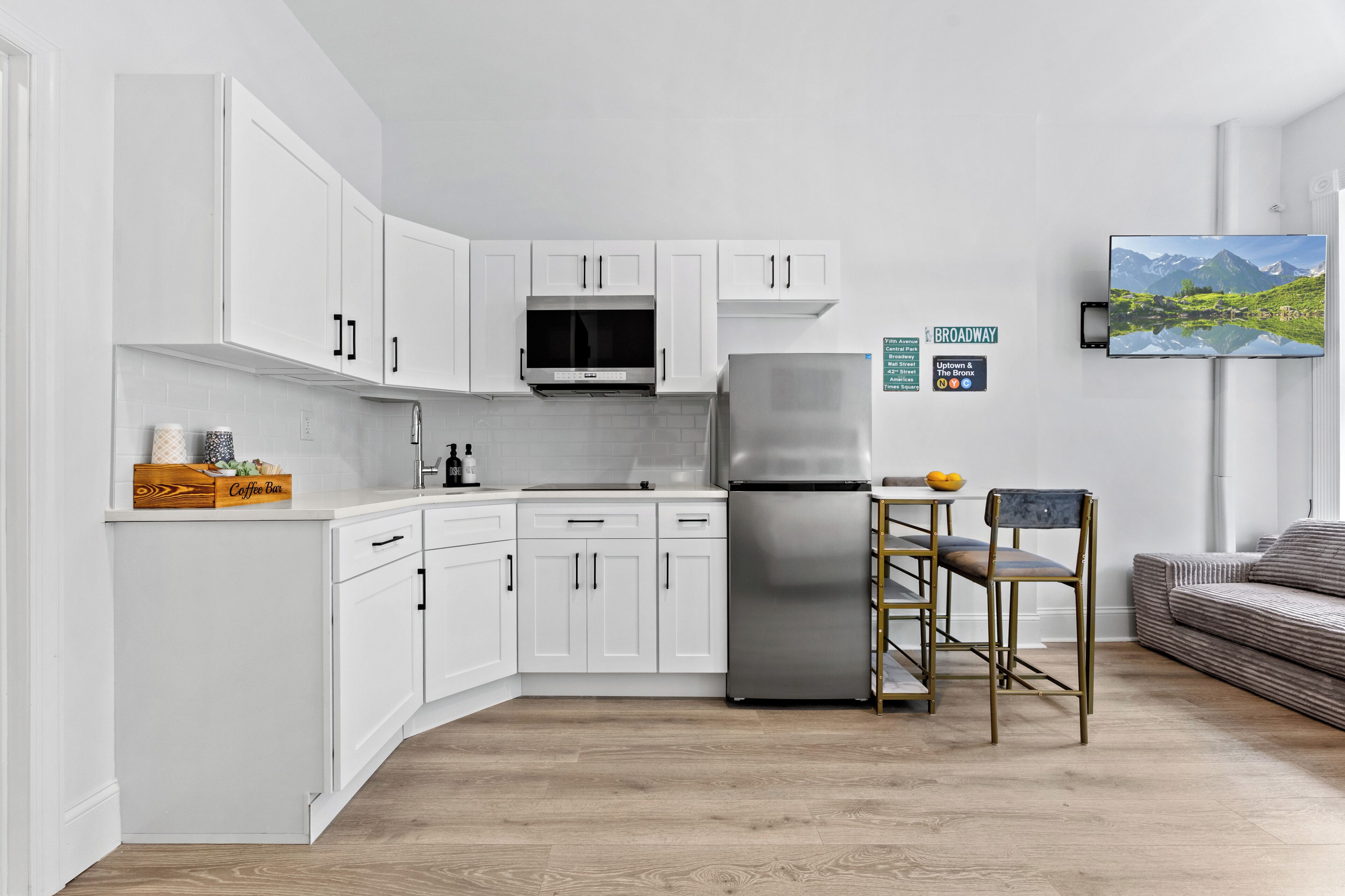 Una cocina moderna con armarios blancos, un refrigerador de acero inoxidable y una barra para café.
